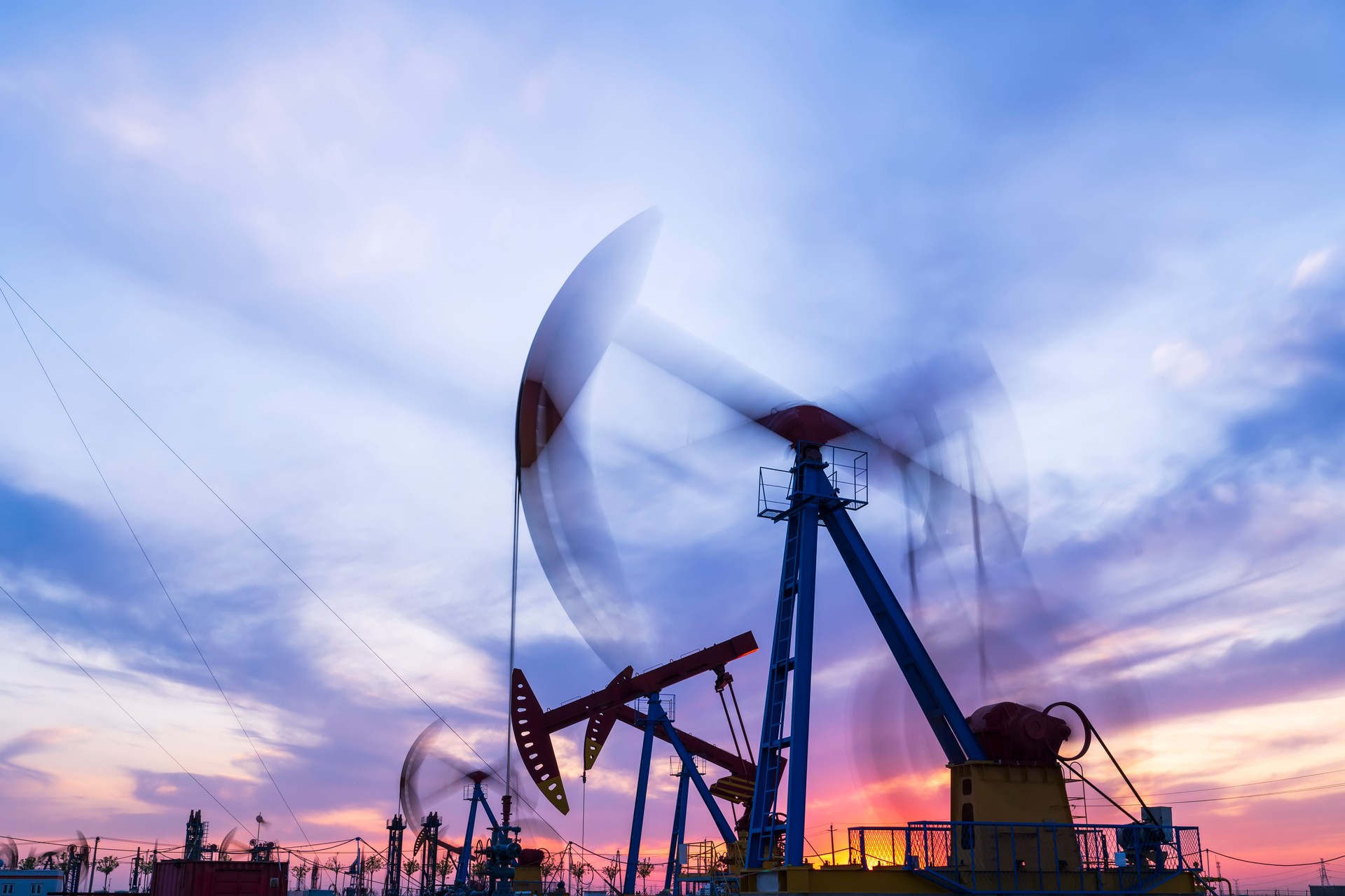 Oil field site, in the evening, oil pumps are running, The oil pump and the beautiful sunset reflected in the water